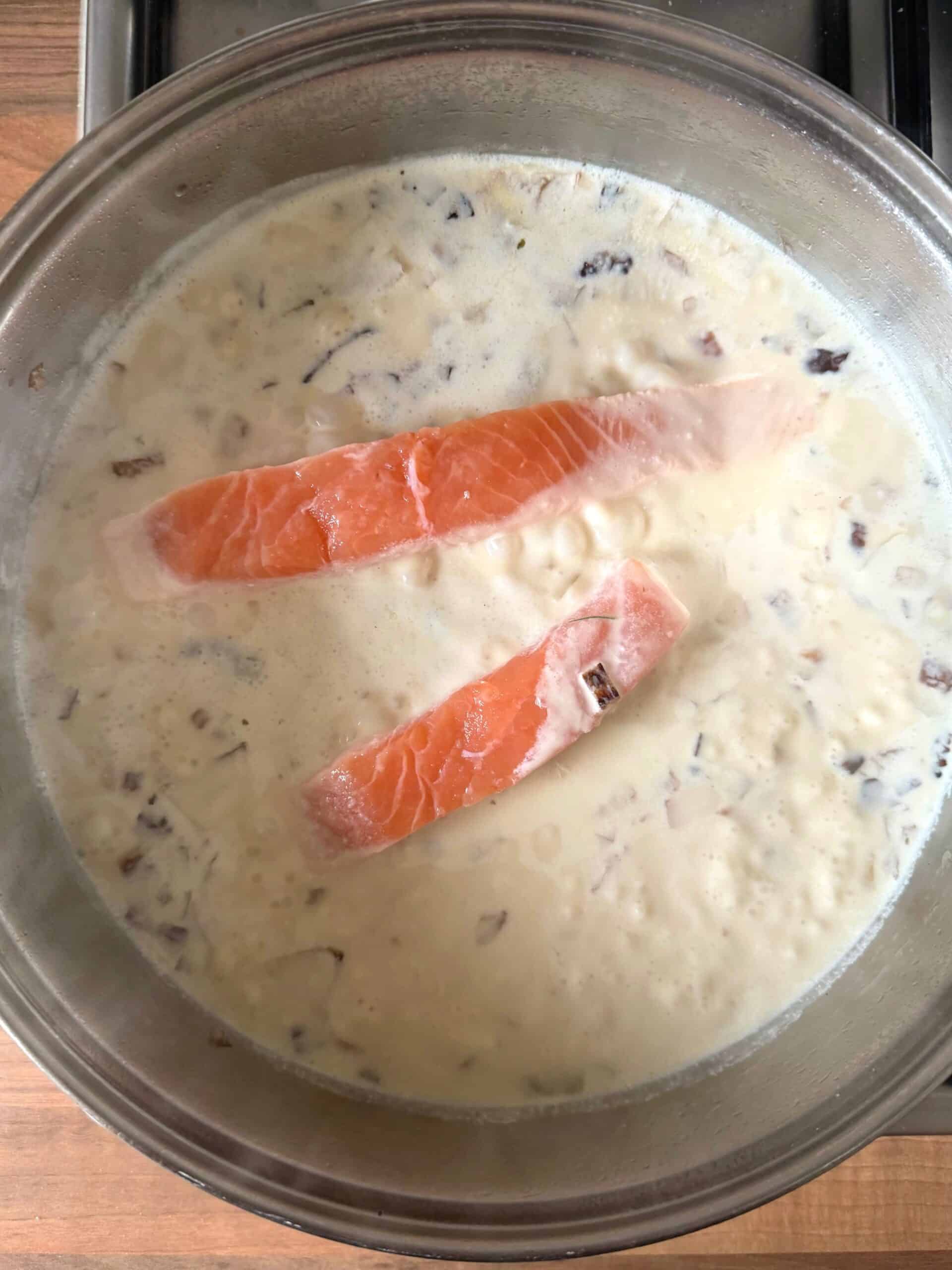 salmon poaching in a pan with cream sauce