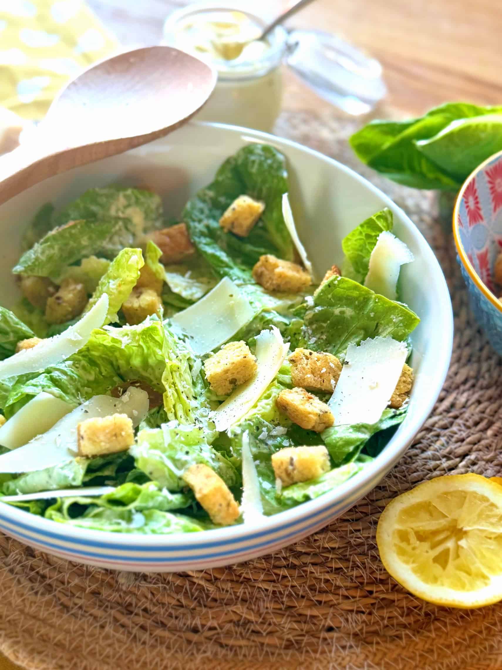 Caesar salad in bowl with wooden serving spoon 