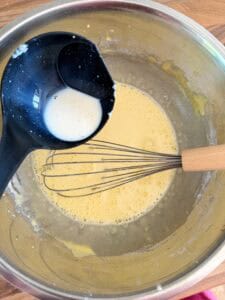 adding hot milk to eggs