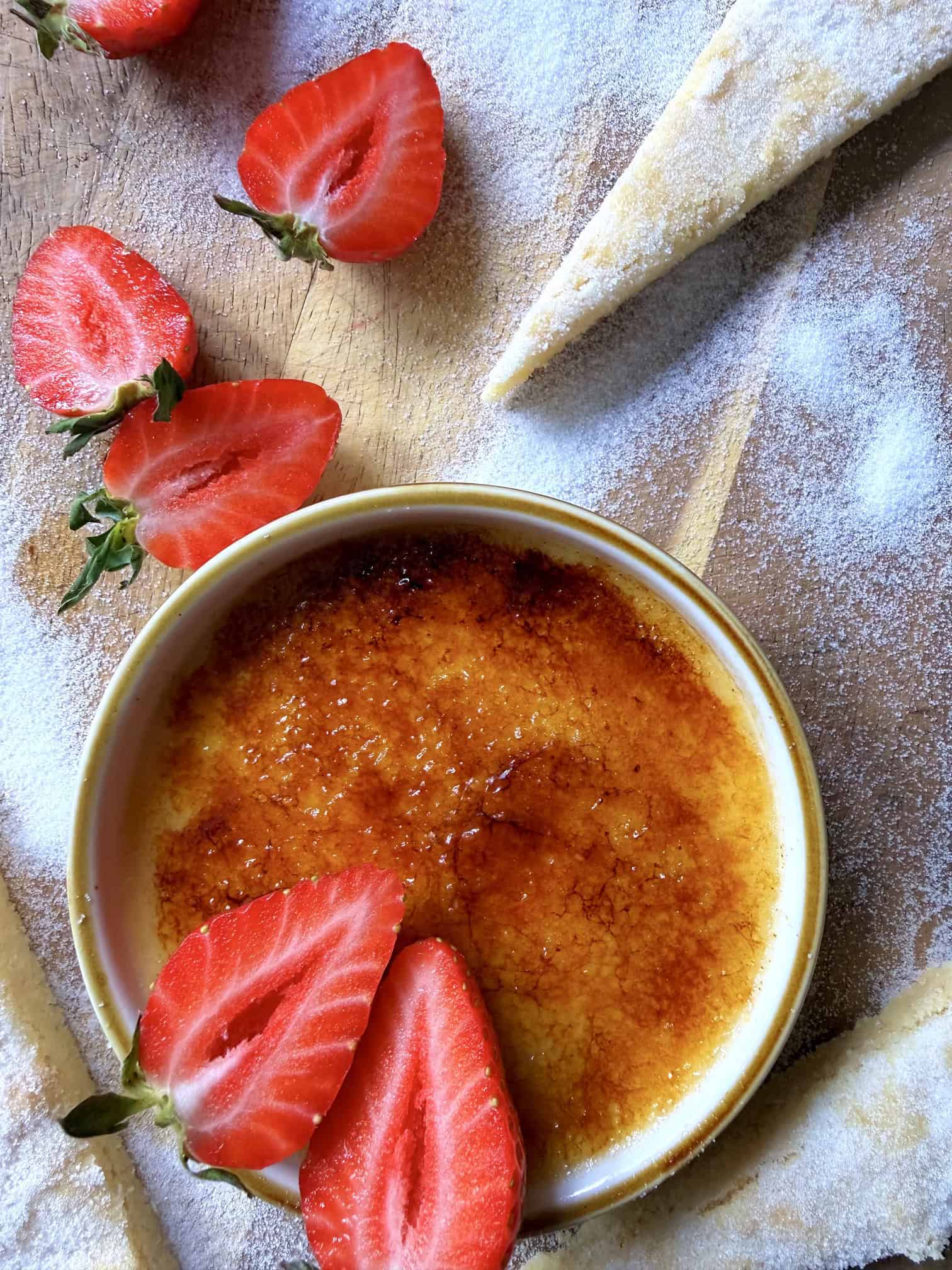 creme brulee with shortbread and bright red strawberries and sugar