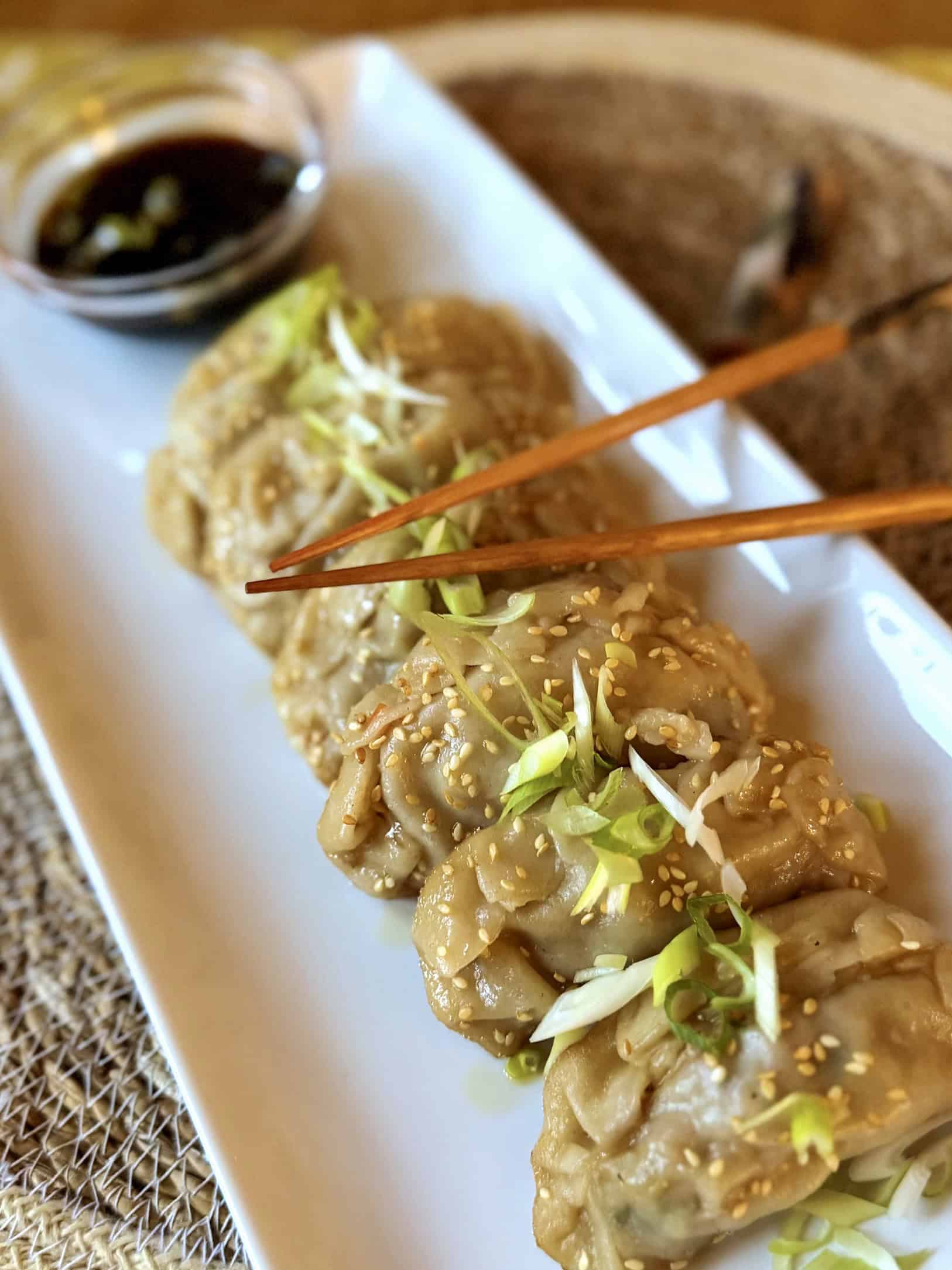 Asian style potsticker dumplings on a plate with chopsticks and dipping sauce