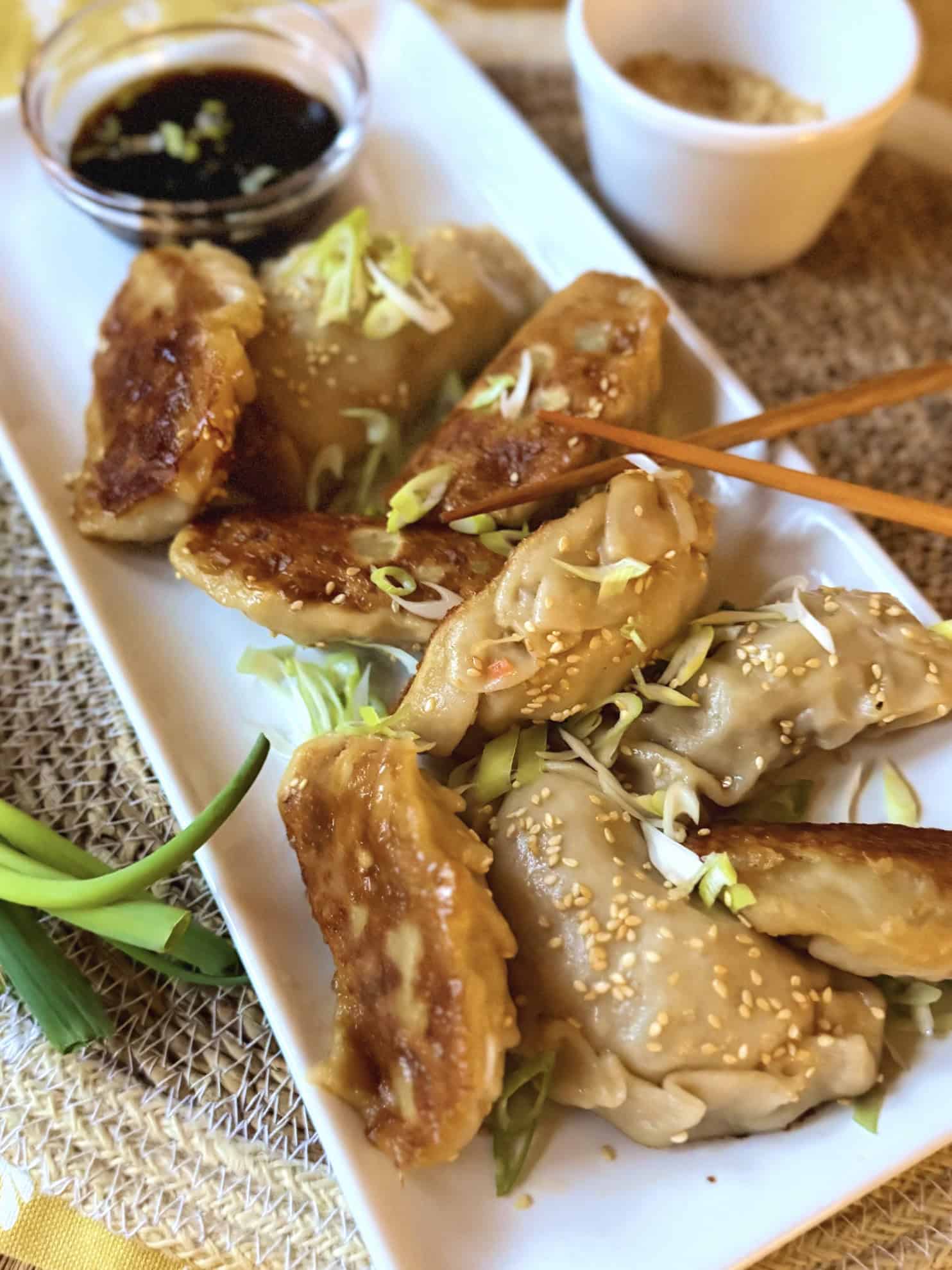 Asian pork potstickers with dipping sauce and toasted sesame seeds