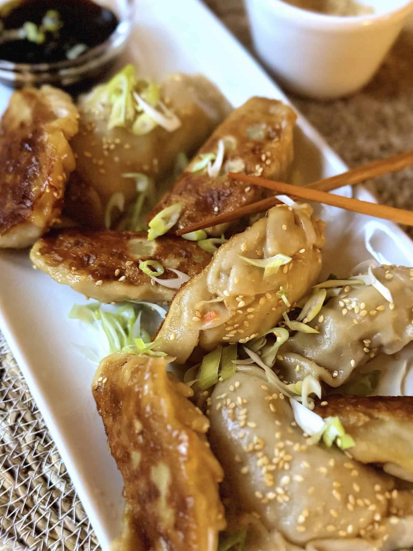 Cooked potstickers with chopsticks and dipping sauce