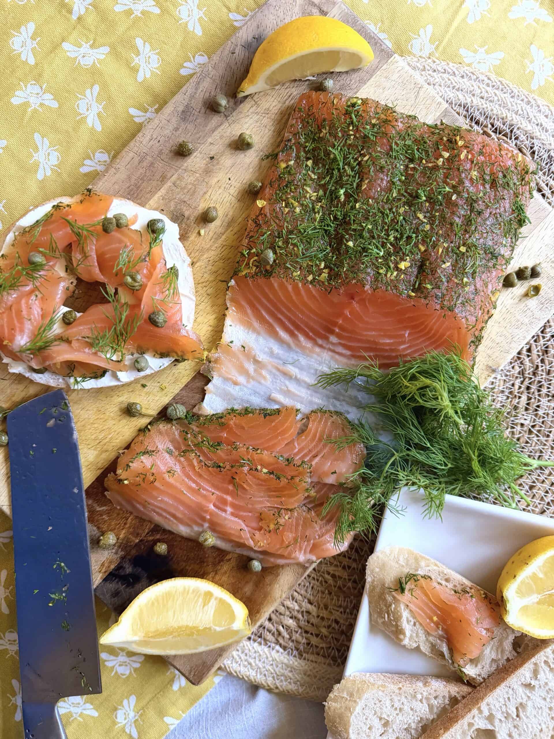 salmon gravlax on a chopping board with a salmon gravlax bagel with green dill