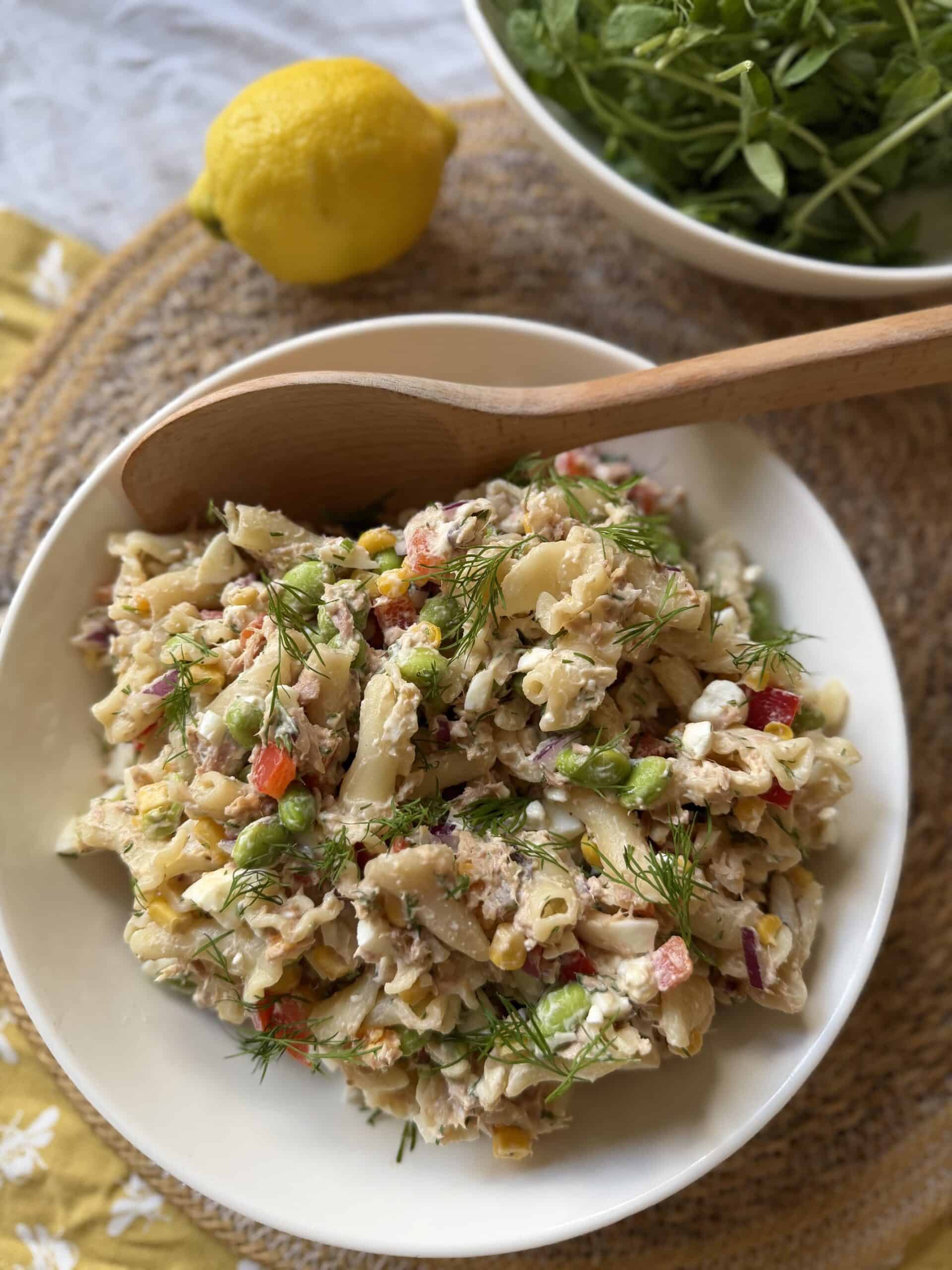 Hiigh protein tuna pasta salad in bowl with lemon overhead short