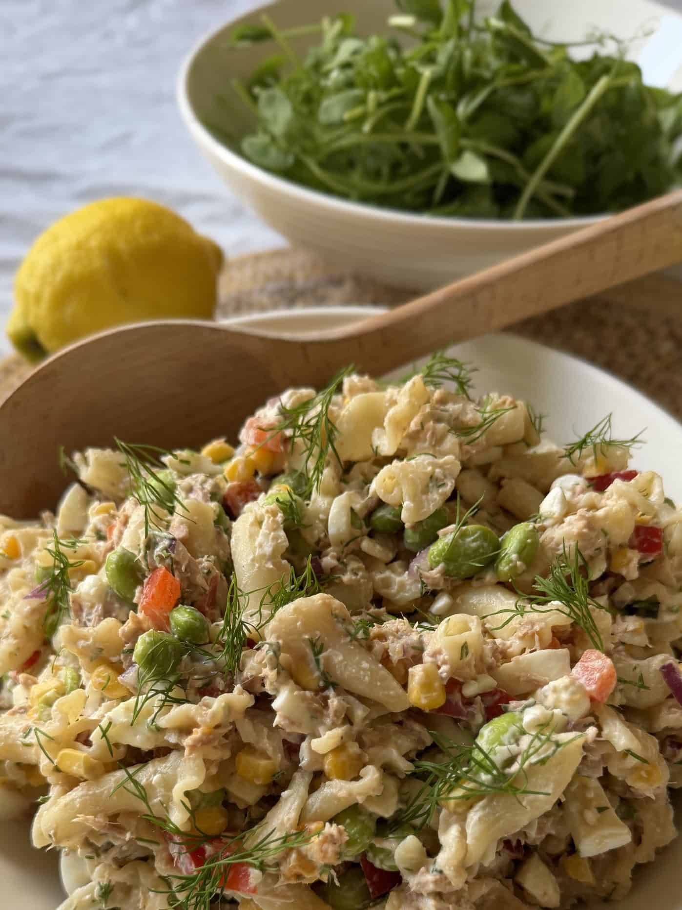 Close up of tuna pasta salad with yellow lemon and green leaves