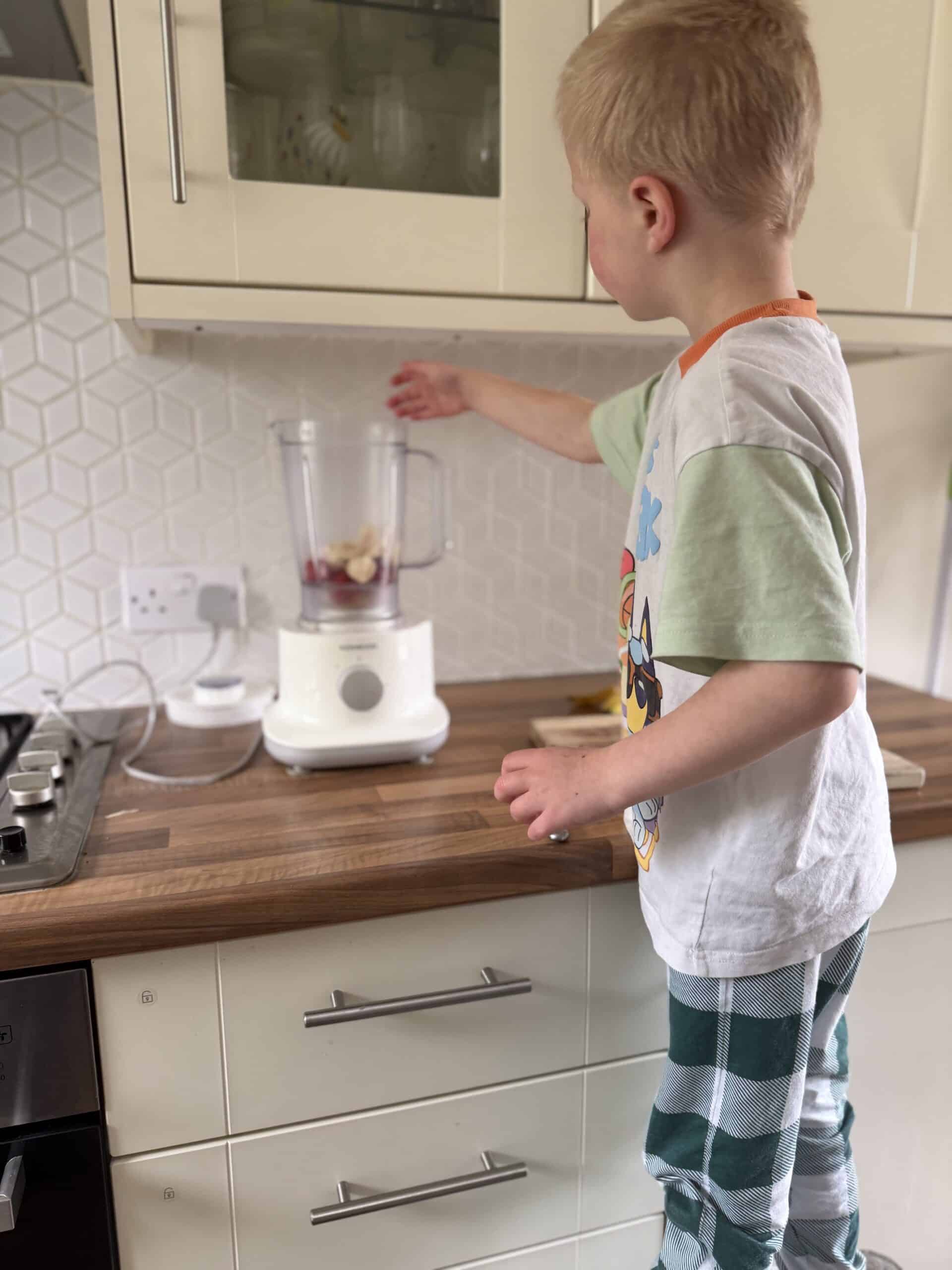 child adding fruit to blender