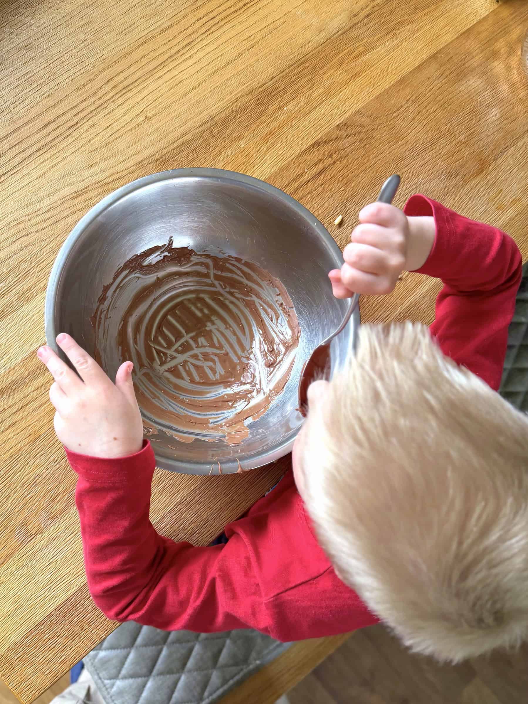 Boy licking the spoon with chocolate on it