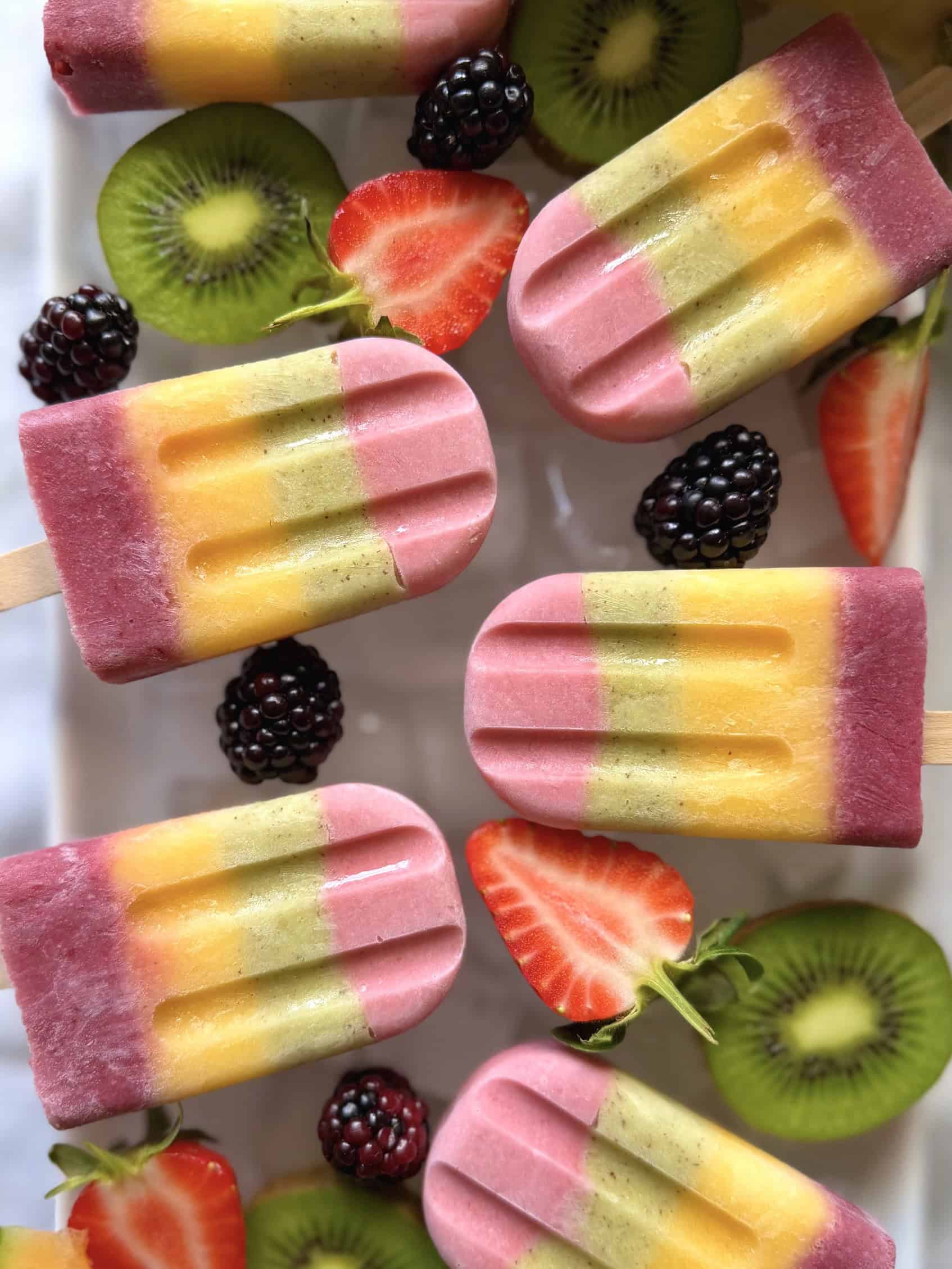 fruit ice lollies on ice with fresh fruit