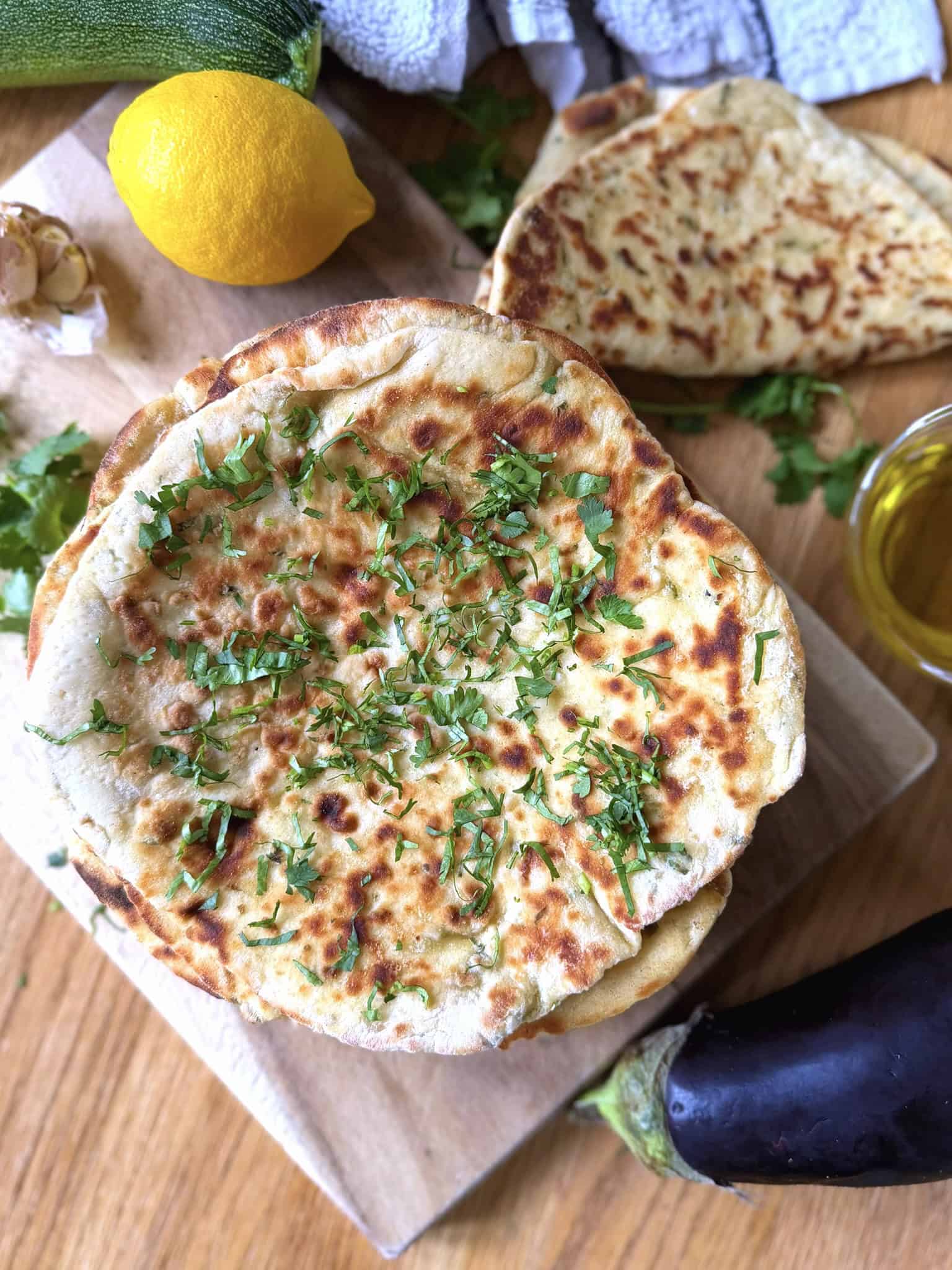 flatbreads on a chopping board with lemon, oil, parsley and garlic