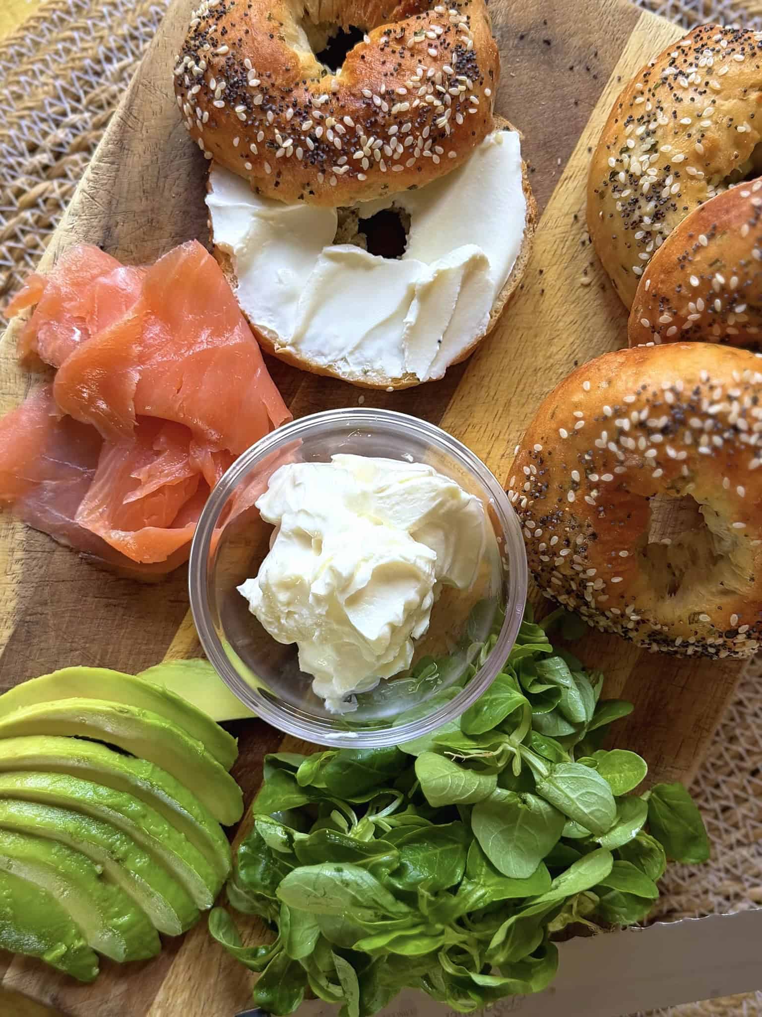 cottage cheese bagels, smoked salmon, avocado and cream cheese on a chopping board
