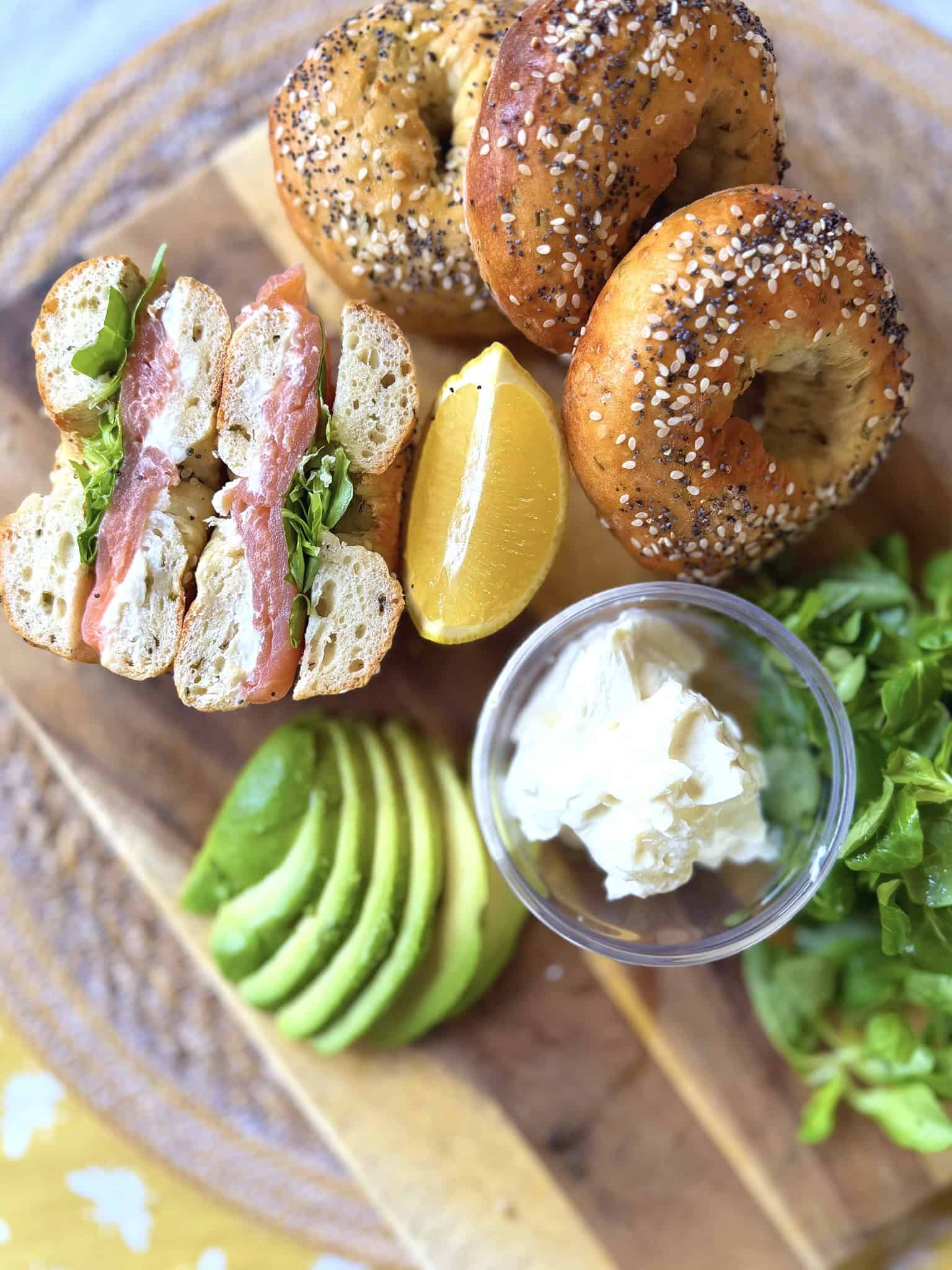 cottage cheese bagels with smoked salmon, avocado, lemon and cream cheese on a chopping board