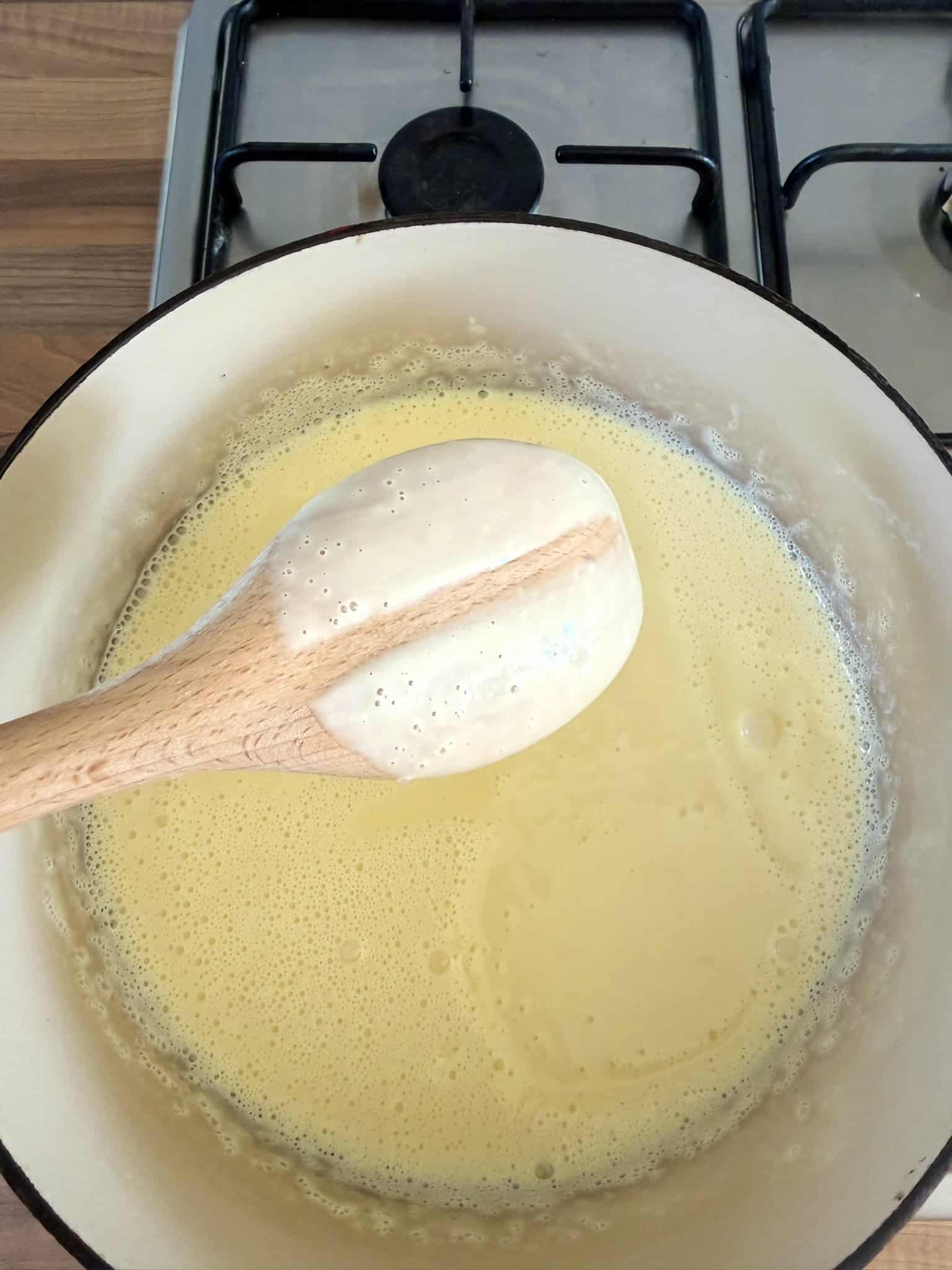 Custard thickening in a pot covering the back of a spoon