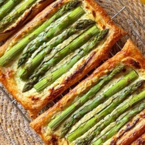 3 asparagus puff pastry tarts in a row on a cooling rack