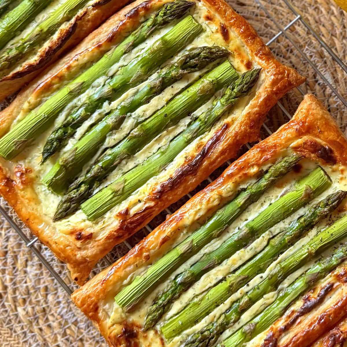 3 asparagus puff pastry tarts in a row on a cooling rack
