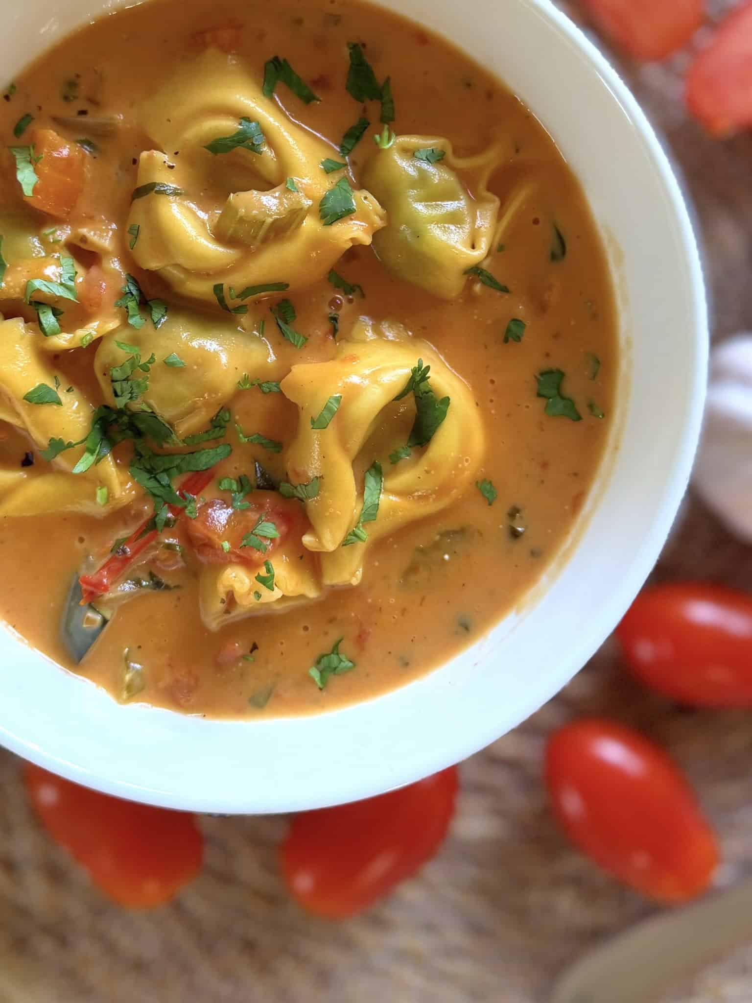 creamy Italian tortellini soup close up in a white bowl