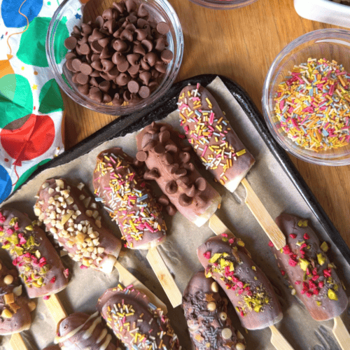 Chocolate bananas on a tray with assorted toppings