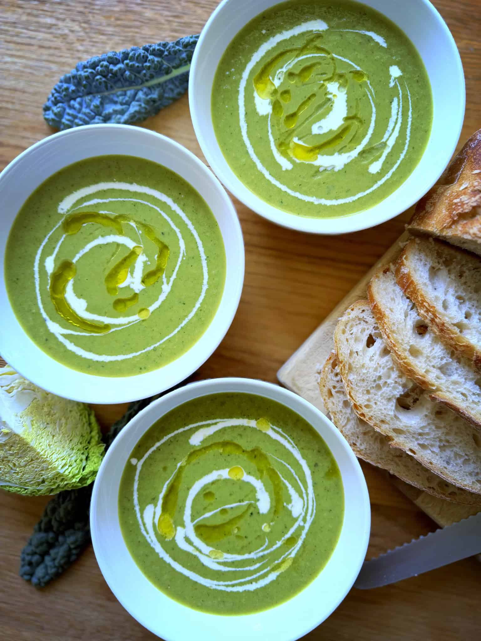 3 bowls of green soup with bread