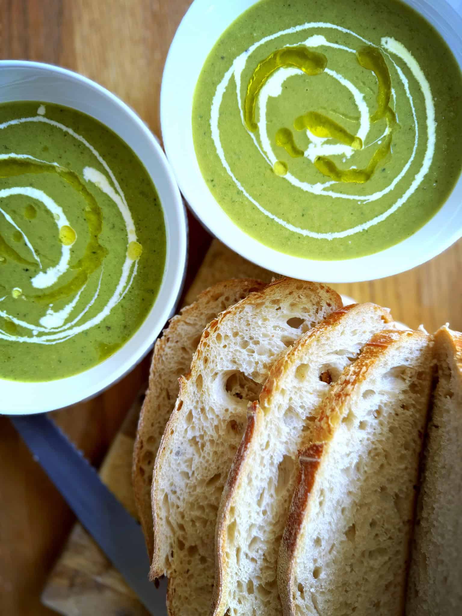 green soup with drizzle of cream and oil with sour dough bread