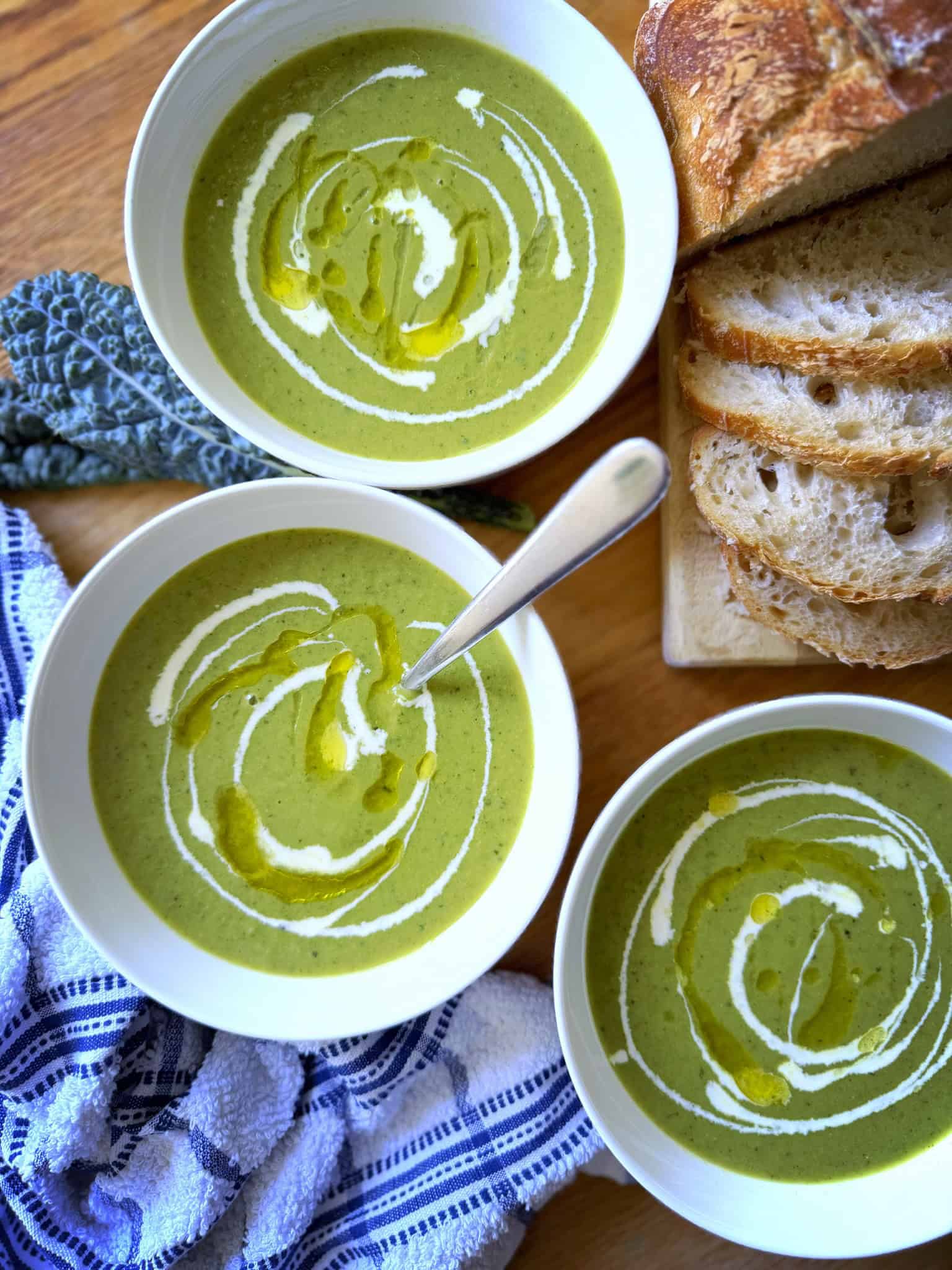 3 bowls of green soup with sour dough bread